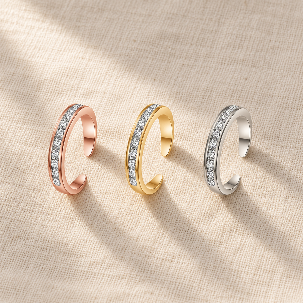 Three adjustable toe rings in rose gold, gold and steel finishes laid out on linen