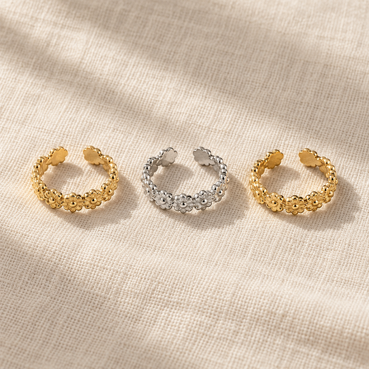 Floral adjustable toe rings in gold and steel finishes laid out on linen