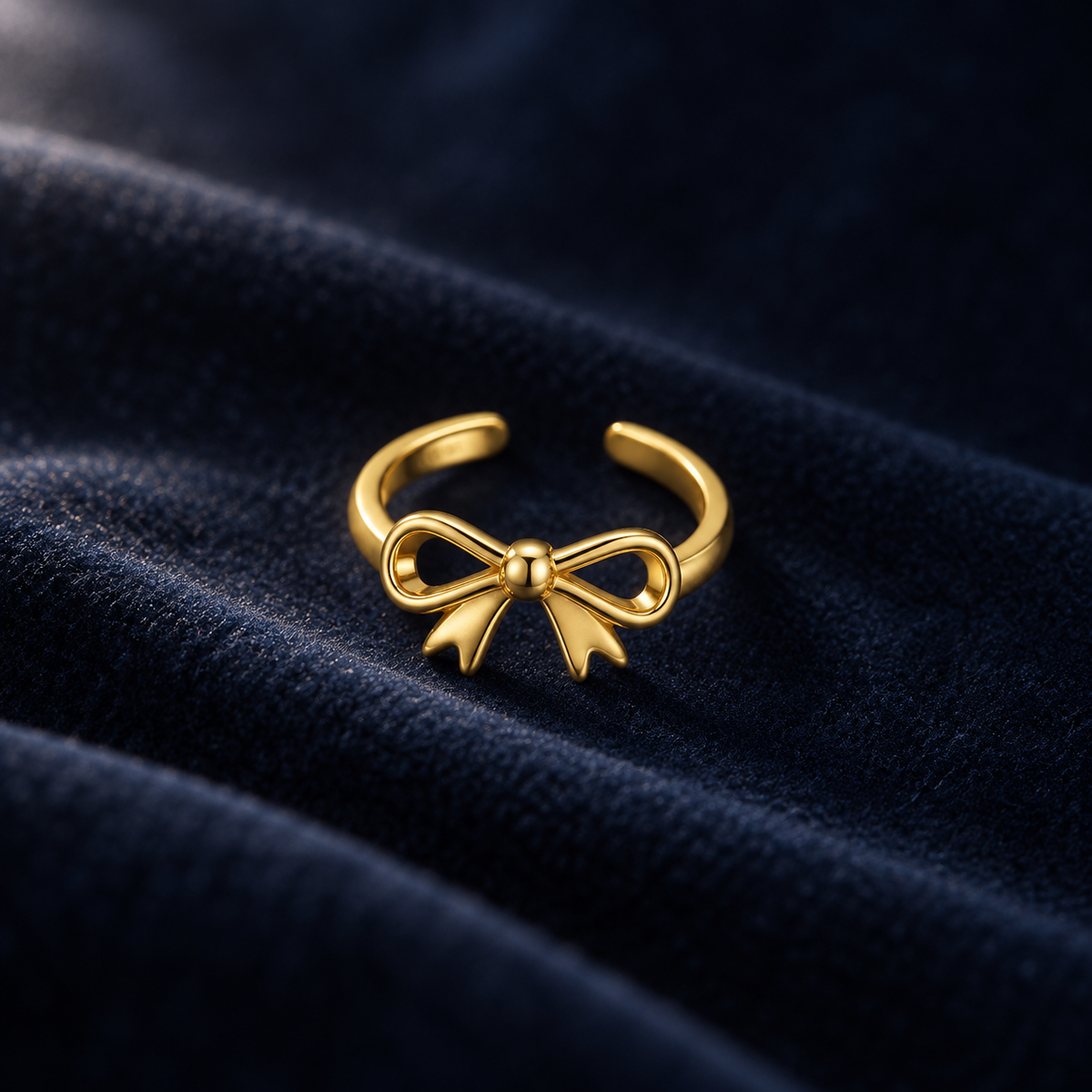 Gold-tone bow toe ring on deep navy velvet